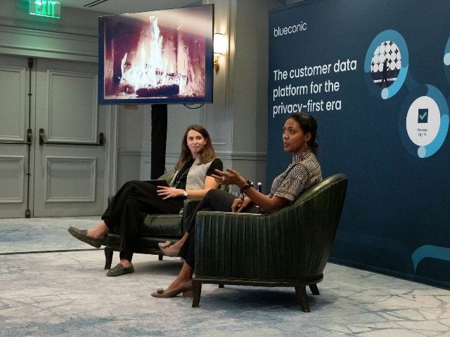 On stage at a customer conference by BlueConic, sitting down are Cory Munchbach, CEO in the background, and a customer, unidentified, in the foreground.