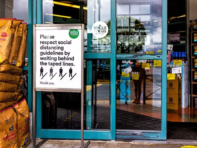 A storefront with a sign outside on social distancing guidelines. - brick and mortar concept