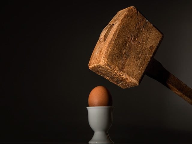 wooden hammer suspended above an egg