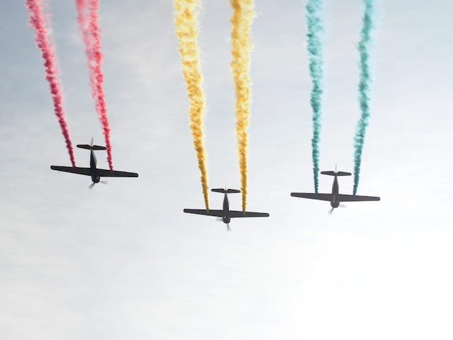 three planes in a flight show, all giving off different brightly colored exhaust
