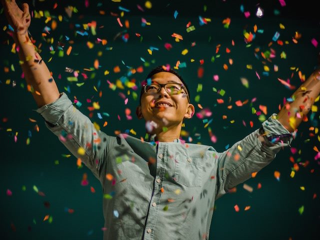 happy person with arms raised surrounded by confetti