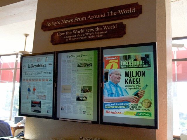 Newspapers inside three glass cases hung on a wall.
