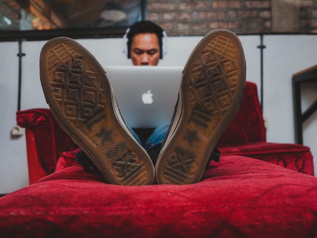 man working with his feet up on a red couch
