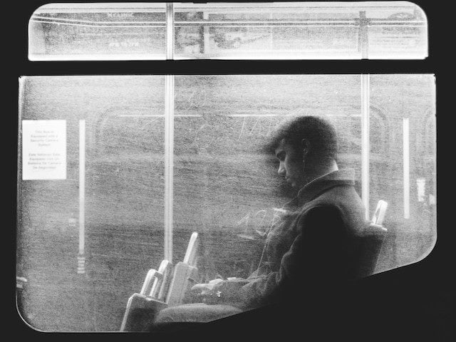 man on public transportation staring at his phone