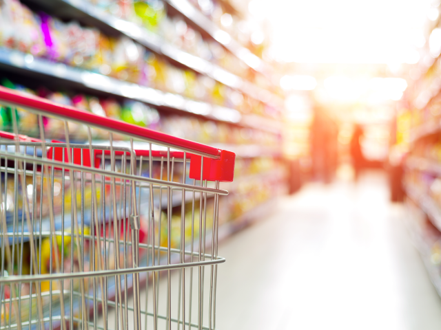 A shopping cart pointing down an infinite aisle of groceries - retail