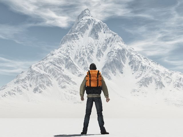 A man wearing climbing gear stands before a snow-covered mountain in piece about change management challenges. 