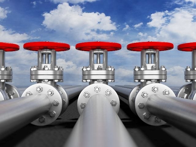 Industrial pipelines and valves on a background of a blue sky with clouds in piece about hybrid clouds and data pipelines. 