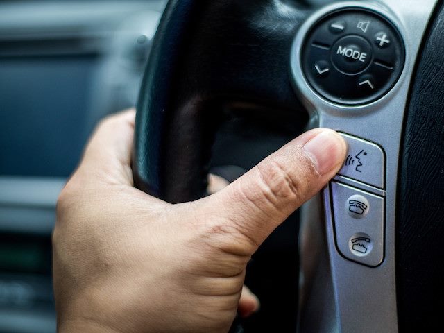 close up of person's hand turning on voice control in car