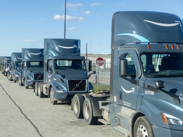 Line of parked Amazon trucks at a transport hub. 