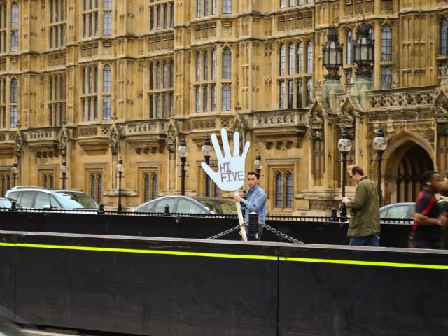man holding a giant cardboard hand with "high five" written on it