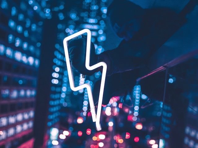 person holding neon sign of a thunderbolt over Chicago traffic