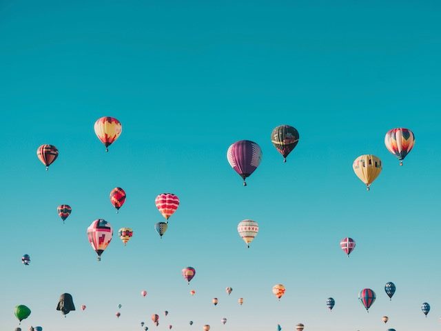multiple passenger balloons launching into a clear sky