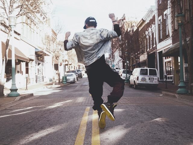 man clicking his heels in the middle of the street as if he doesn't have a care in the world