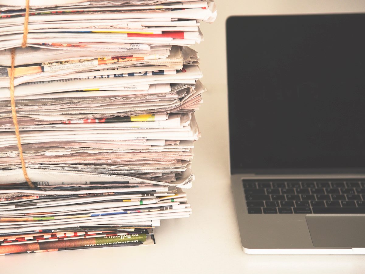 Pile of daily papers with news next to the computer