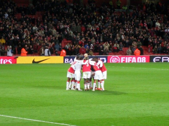 a men's soccer team huddling up on a soccer field.