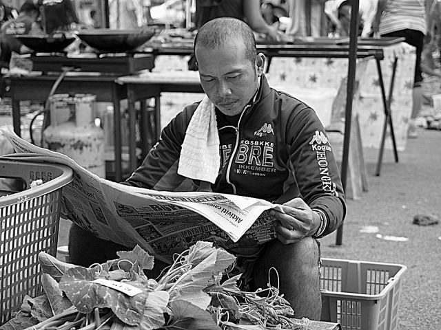 Man sitting down reading a newspaper.