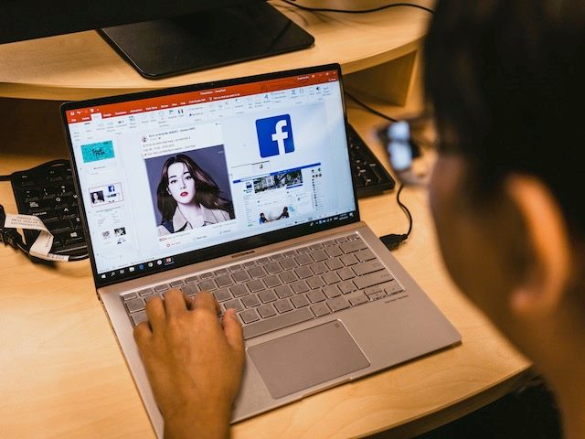 person browsing Facebook on a laptop