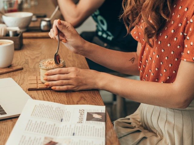 Woman mixing a drink with a newspaper on the table.
