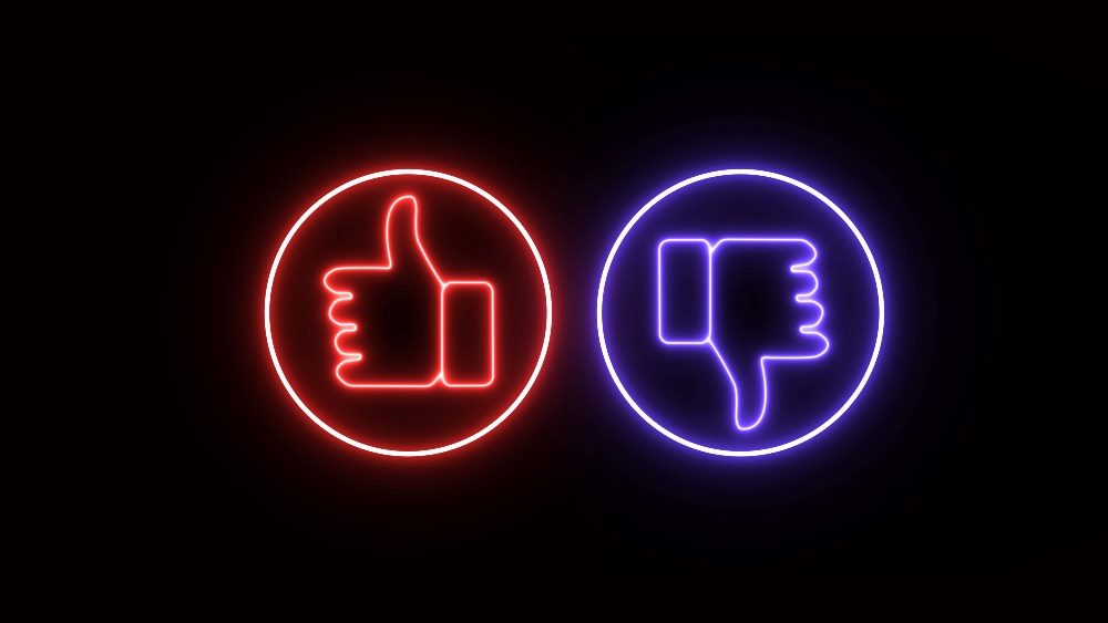 A red neon thumbs up sign surrounded by a circle and a purple neon thumbs down symbol in a circle in piece about user experience analysis and customer journeys.