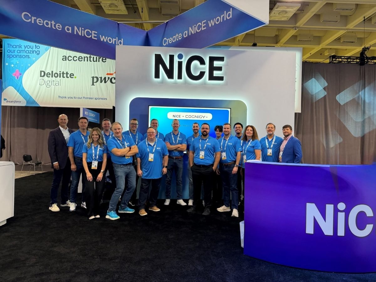 NiCE Software team members pose together at their booth during Salesforce Dreamforce, featuring branding for the NiCE + Cognigy partnership and event sponsor signage in the background.