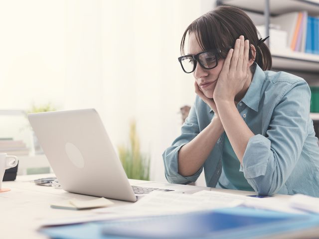 woman sitting in front of her laptop, looking bored