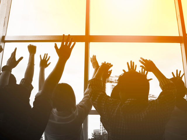 A group of silhouetted customers reaching towards the light in a window