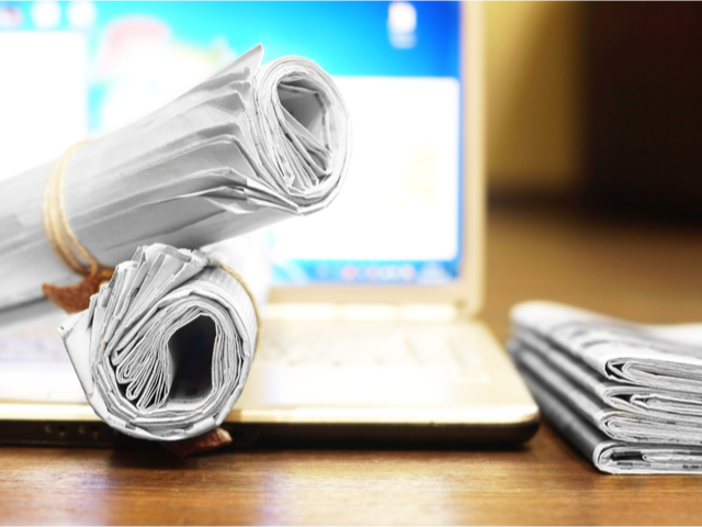 Rolled up newspapers on a laptop computer - news concept