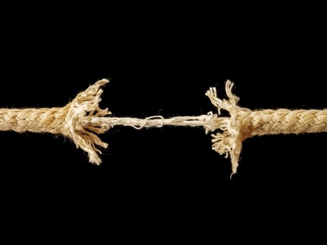 A piece of frayed rope about to break against a dark background representing the tension of trying to win back unhappy customers. 