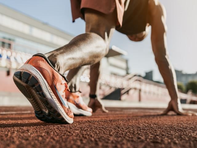 Close up of a male athlete getting ready to start running on track - Getting ready concept