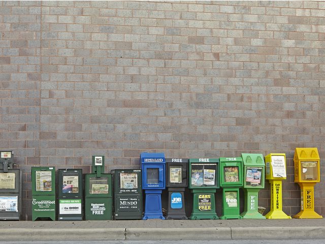 A row of newspaper boxes against a wall.
