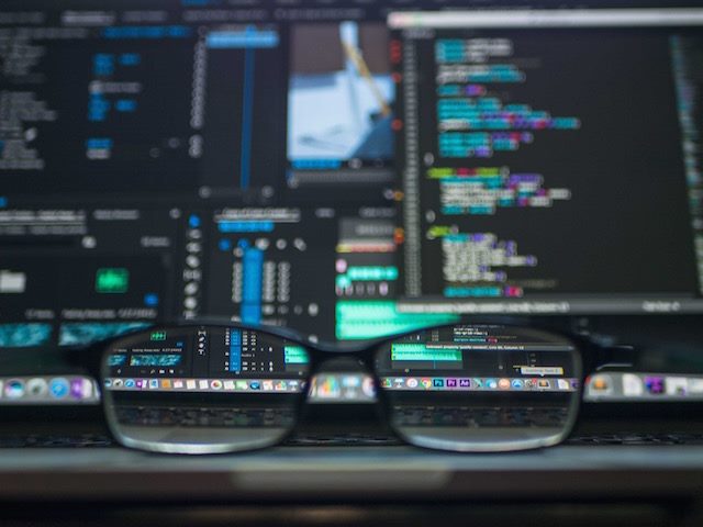 reading glasses in front of several computer monitors