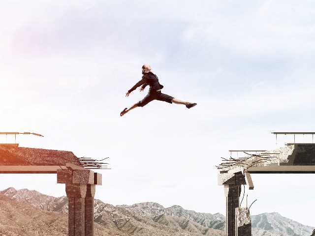 Woman jumping across a broken bridge.