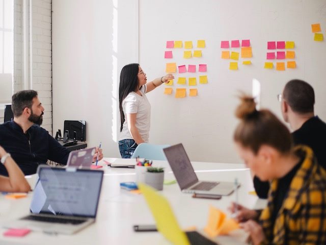 woman standing in front of a sticky-note covered white board