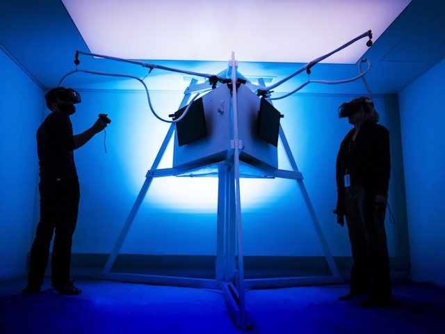 two people with virtual reality goggles on in an immersive experience room