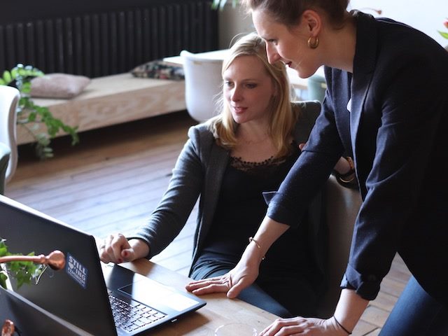 two women looking at a laptop discussing what they see there