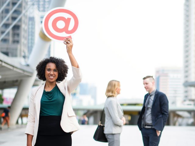 woman holding @ symbol over her head