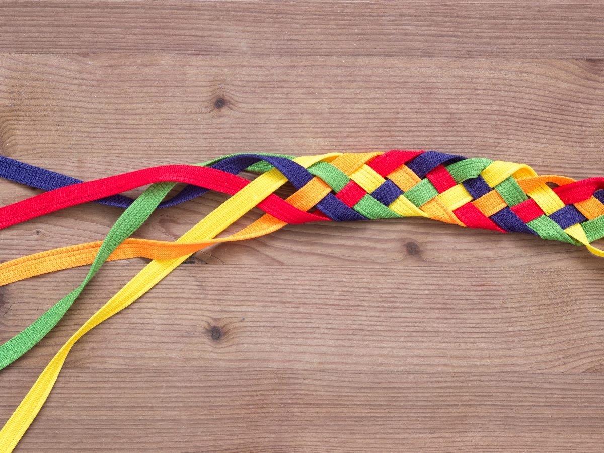 Colorful fabric straps woven together on a wooden surface, symbolizing integration and connection.