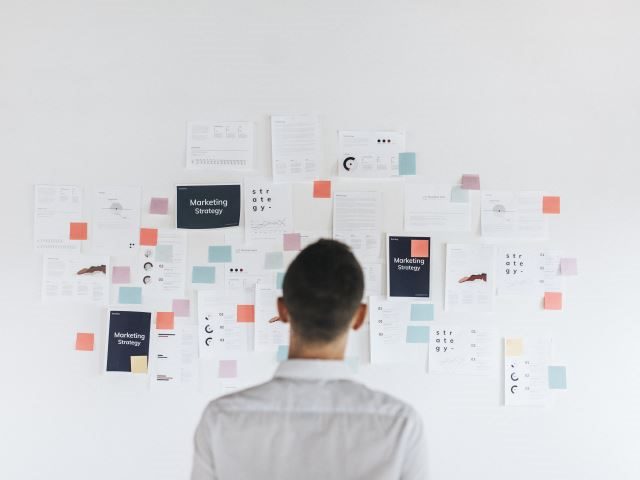 A content strategist laying out his plan on a whiteboard with sticky notes - content strategy concept
