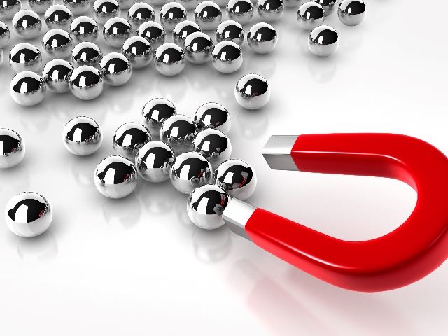 A a red horse-shoe shaped magnet is used to attract shiny metal balls, representing customer retention marketing. 