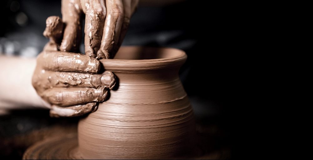 Close-up image of hands molding a clay pot on a pottery wheel, illustrating the careful shaping process, akin to the concept of "dogfooding" in product development, where products are tested and refined internally.