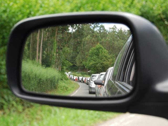 Rearview mirror view showing line of cars in traffic.