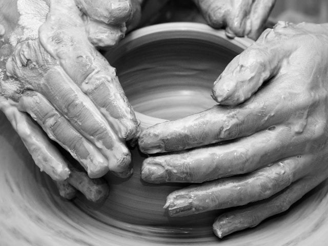Women hands in clay in the process of making crockery on pottery wheel, representing how customer experience leaders are reshaping CX by using generative AI in customer experience.