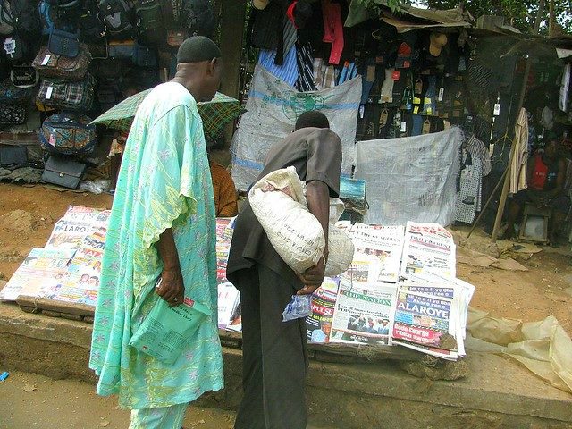 Two people look over a stack of newspapers.