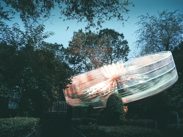 tilt a whirl ride in motion, surrounded by trees