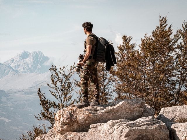 A person with a camera at the top of a cliff