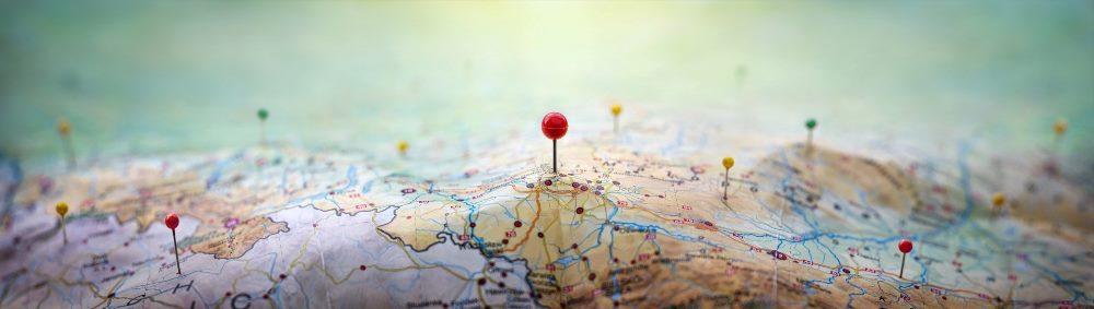Pins on a geographic map curved like mountains against a green background.
