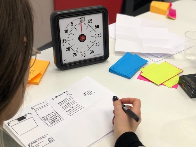 woman wireframing on paper with sticky notes nearby