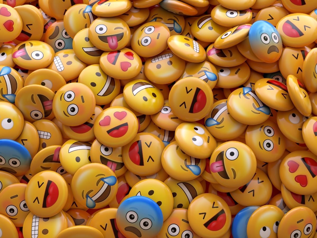A colorful pile of 3D emoji faces showing a range of expressions including laughter, love, surprise and silliness, symbolizing diverse emotions and reactions.