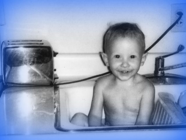 boy bathing in kitchen sink with plugged in toaster
