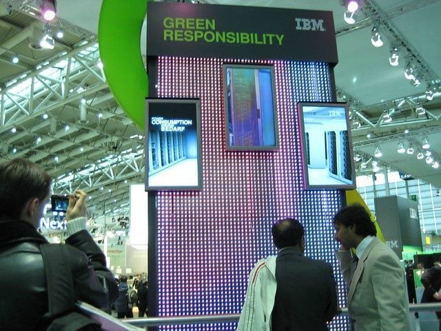 People standing in front of a sign that says "IBM Green Responsibility"